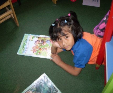 Niña leyendo un libro en el suelo